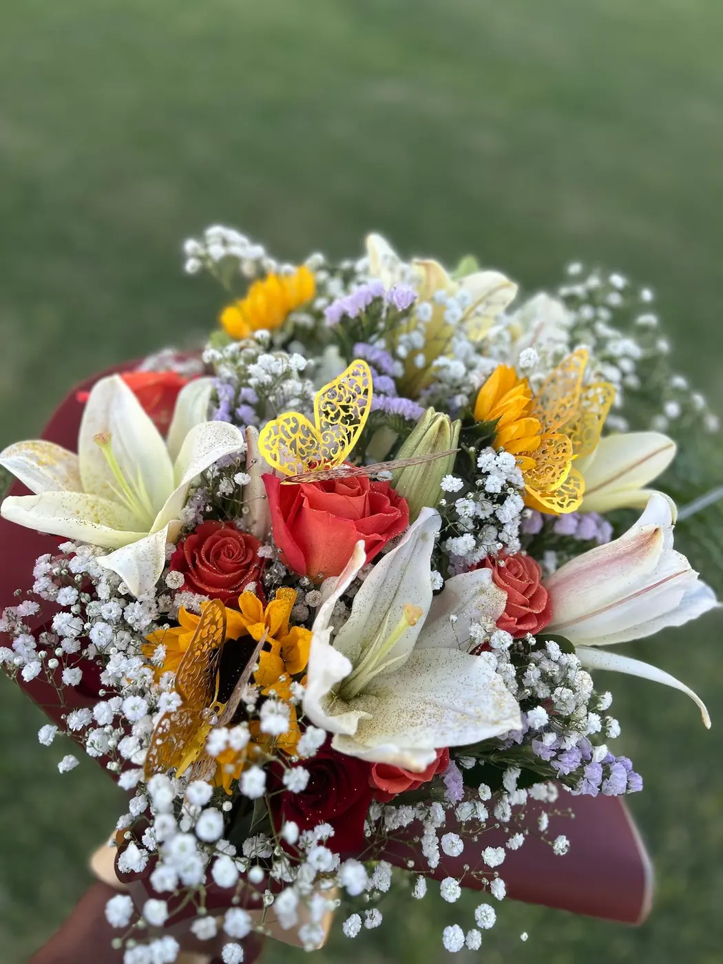 Bouquet of white lilies, sunflowers, roses and baby’s breath outdoors